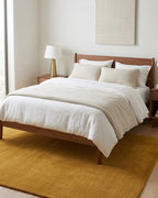 Liso Gold solid hand-tufted wool rug under a bed