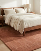 Liso Mocha Mousse solid hand-tufted wool rug under a bed