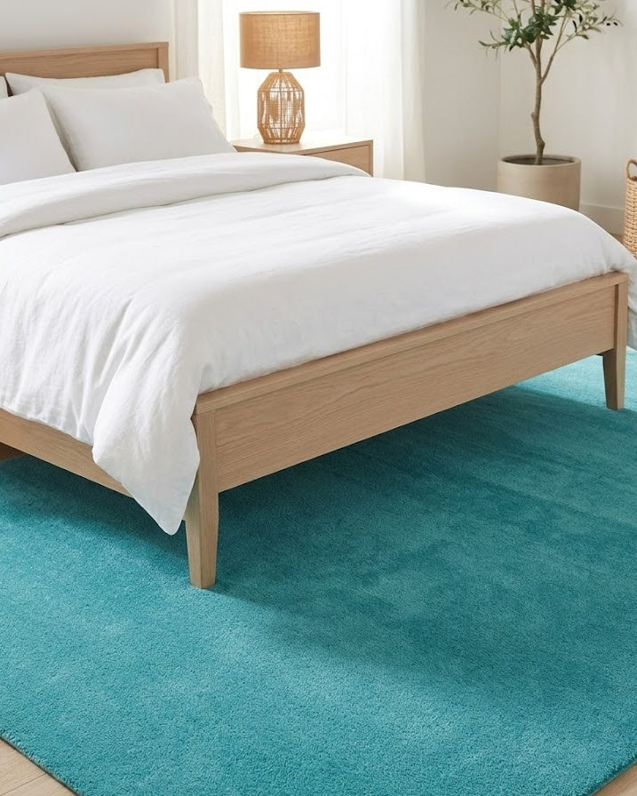 Liso Turquoise solid hand-tufted wool rug under a bed